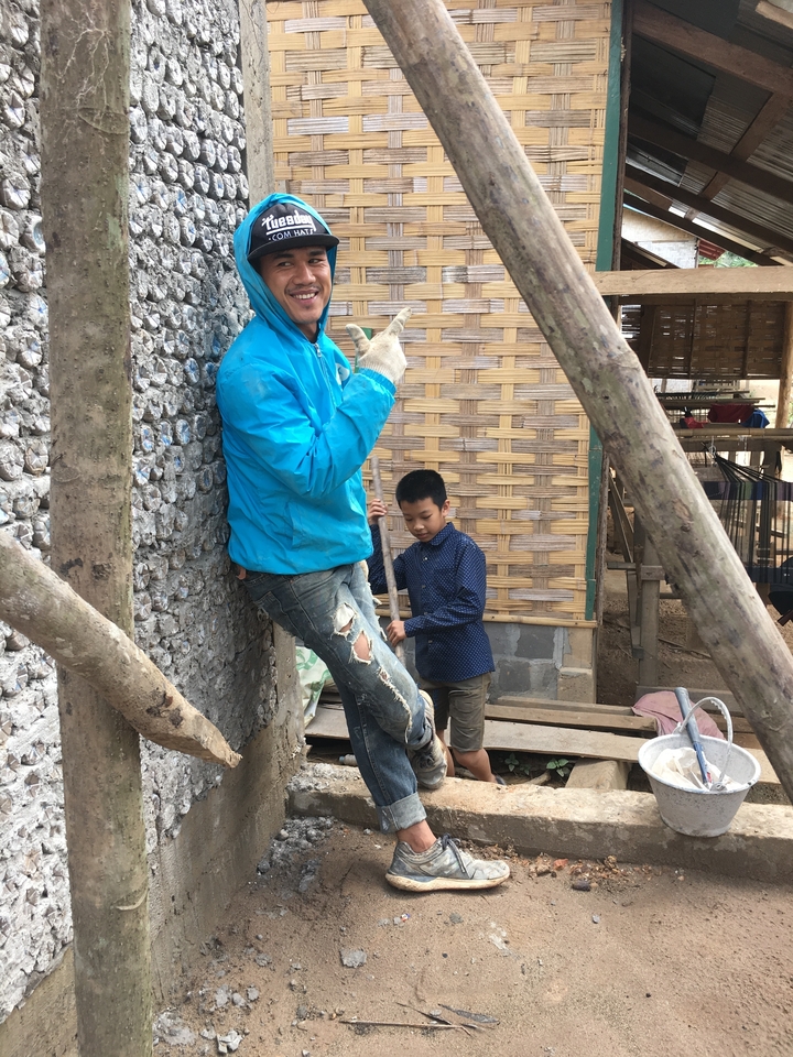 Man leaning against a wall with a child in the background.