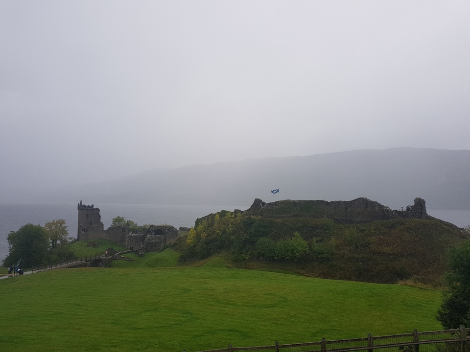 Ruines d'un château au bord d'un lac avec un drapeau.