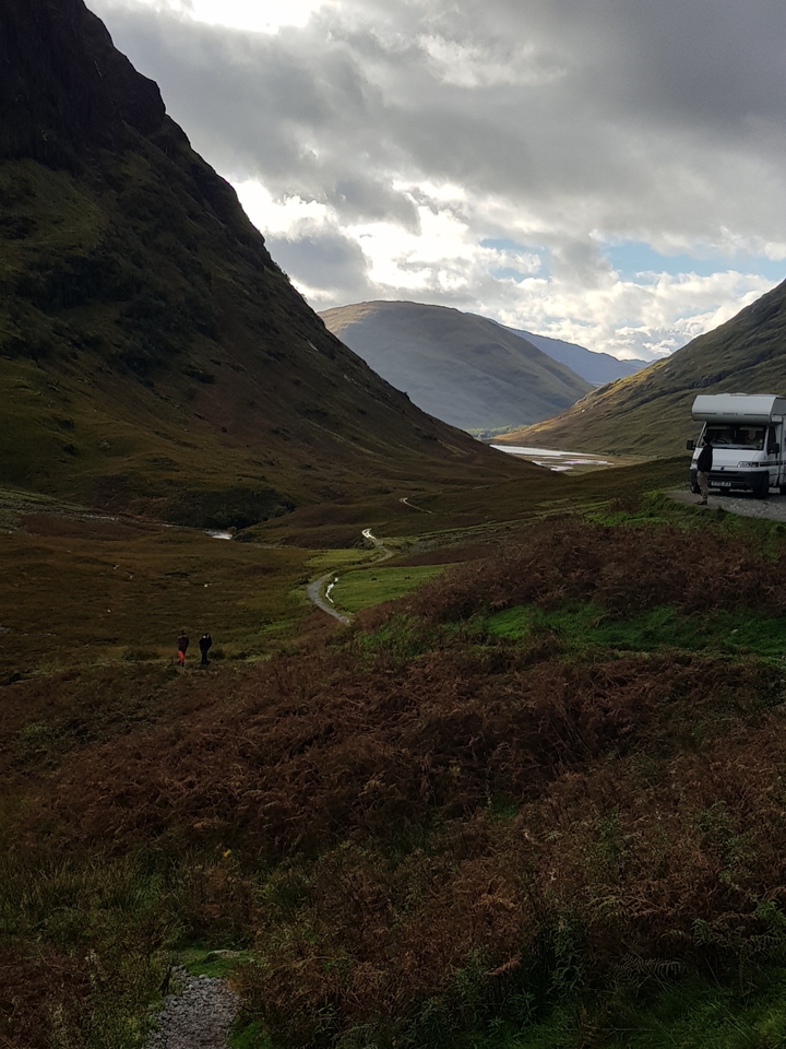 Vallée pittoresque avec un camping-car au bord de la route.