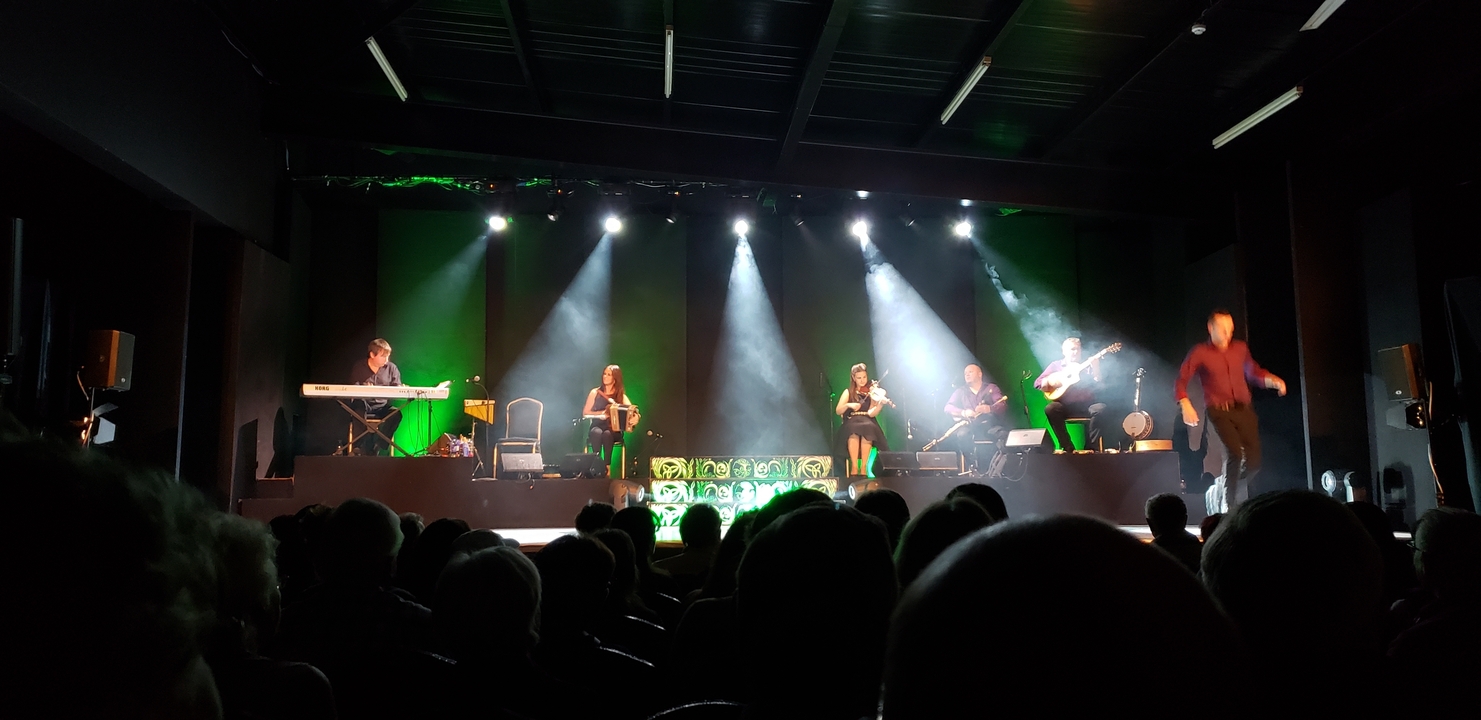 Spectacle en salle avec musiciens et danseurs sur scène.