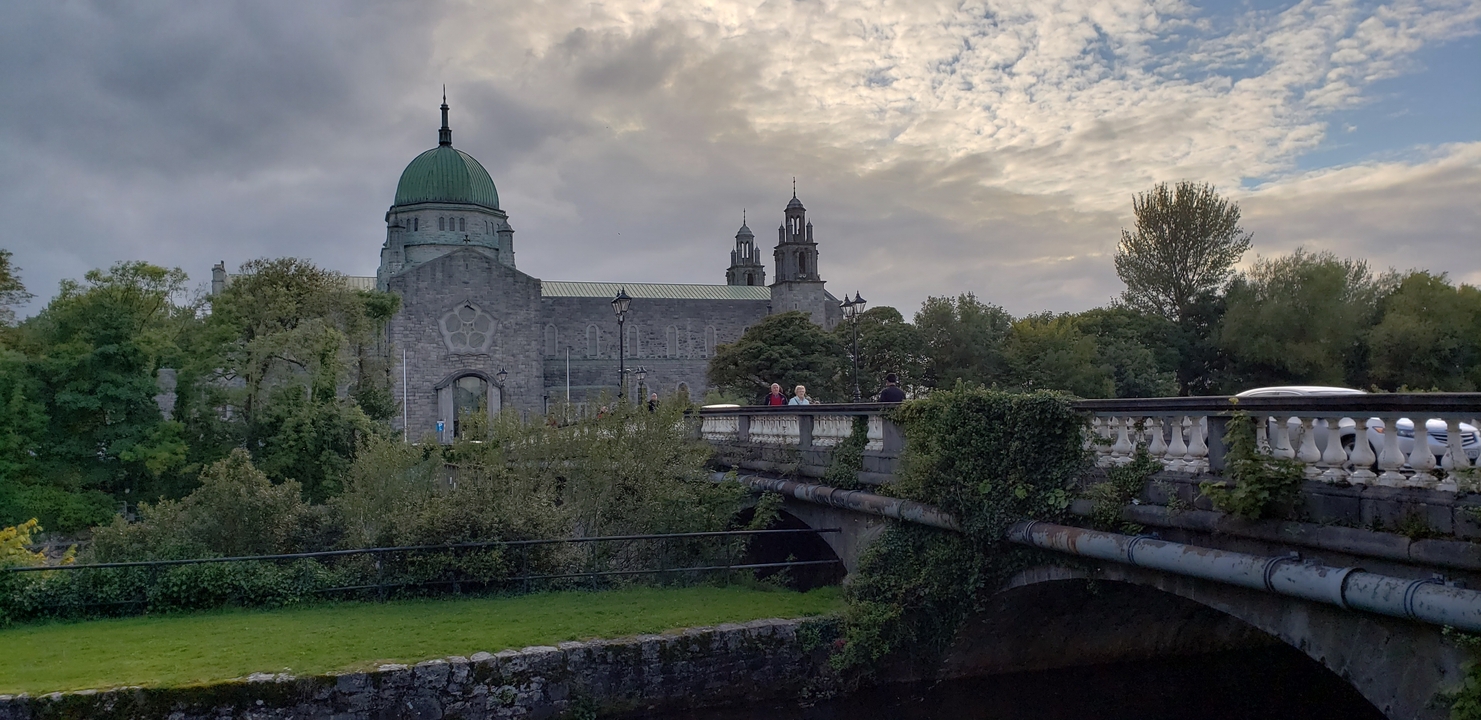 Large stone building in an urban setting, viewed from a bridge.