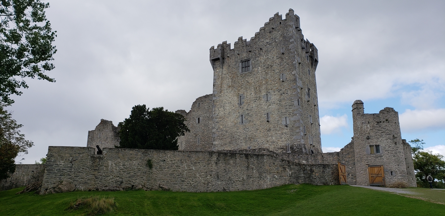 Stone castle with crenulated towers under a cloudy sky.