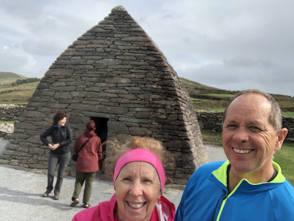 Couple posant devant une maison en pierre en forme de ruche.
