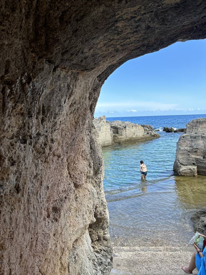 Zone de plage rocheuse avec une personne dans l'eau.