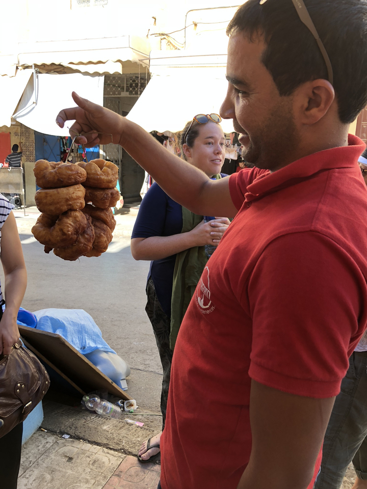 Homme tenant des brochettes d'en-cas frits dans un marché.