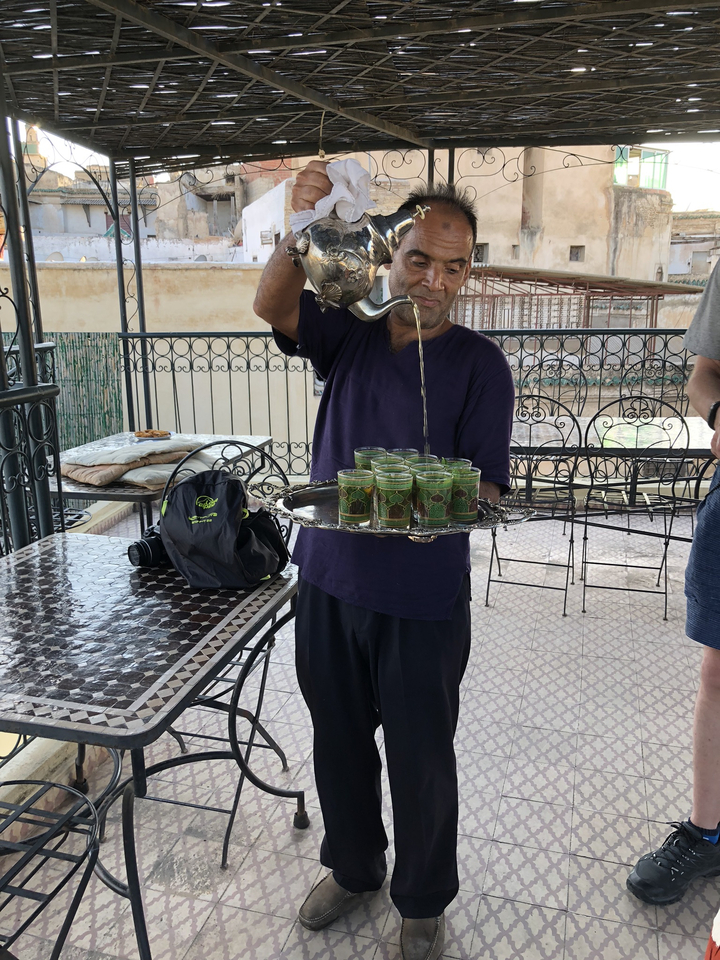 Here's the French translation:
**Homme versant du thé dans des verres sur un plateau.**
