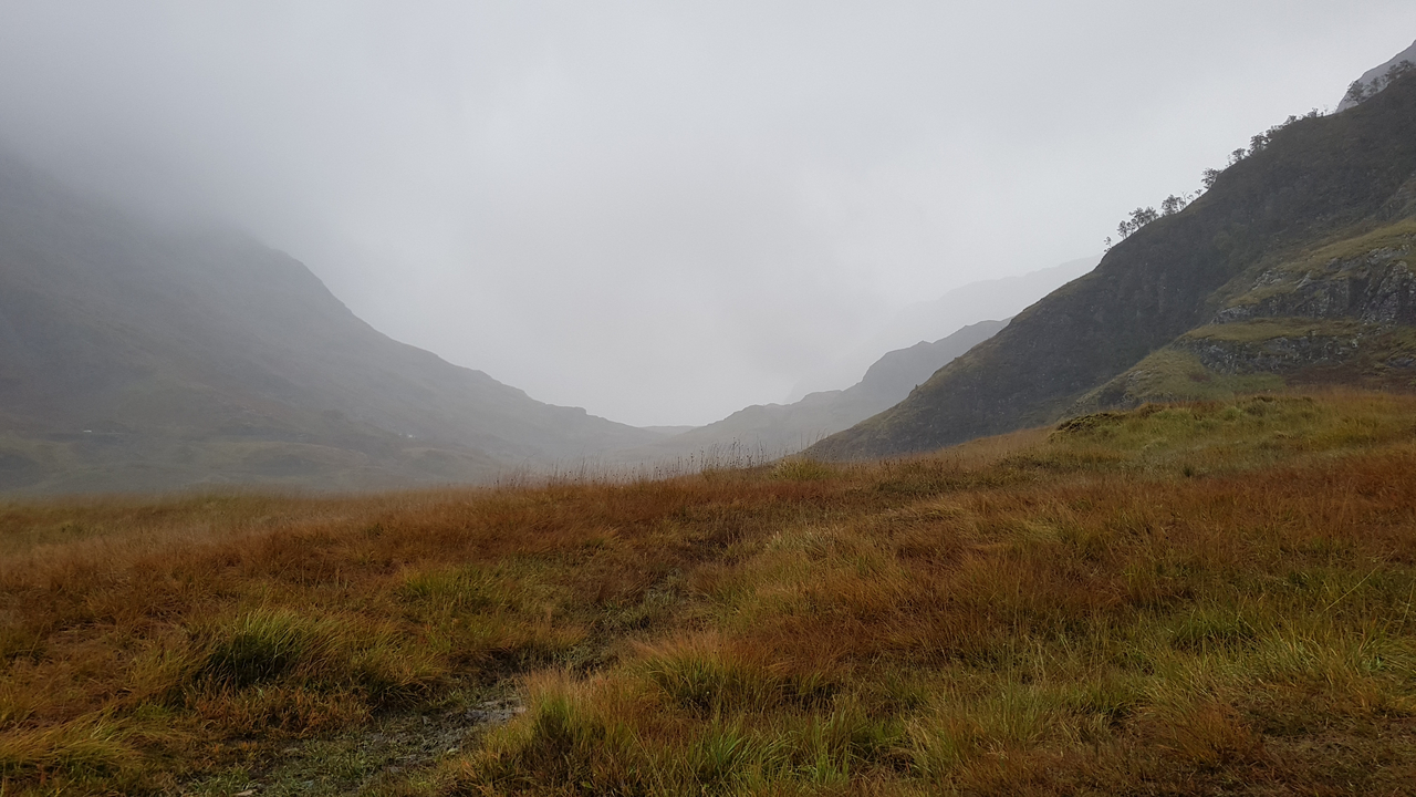 Misty valley with mountainous backdrop.