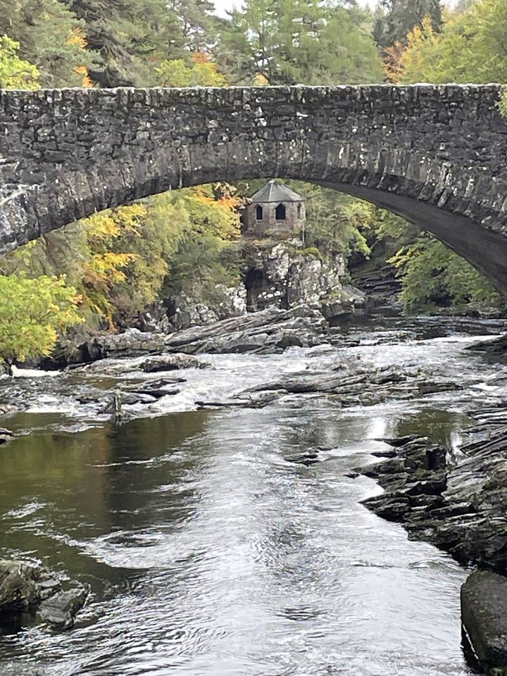 Vieux pont de pierre au-dessus d'une rivière calme.