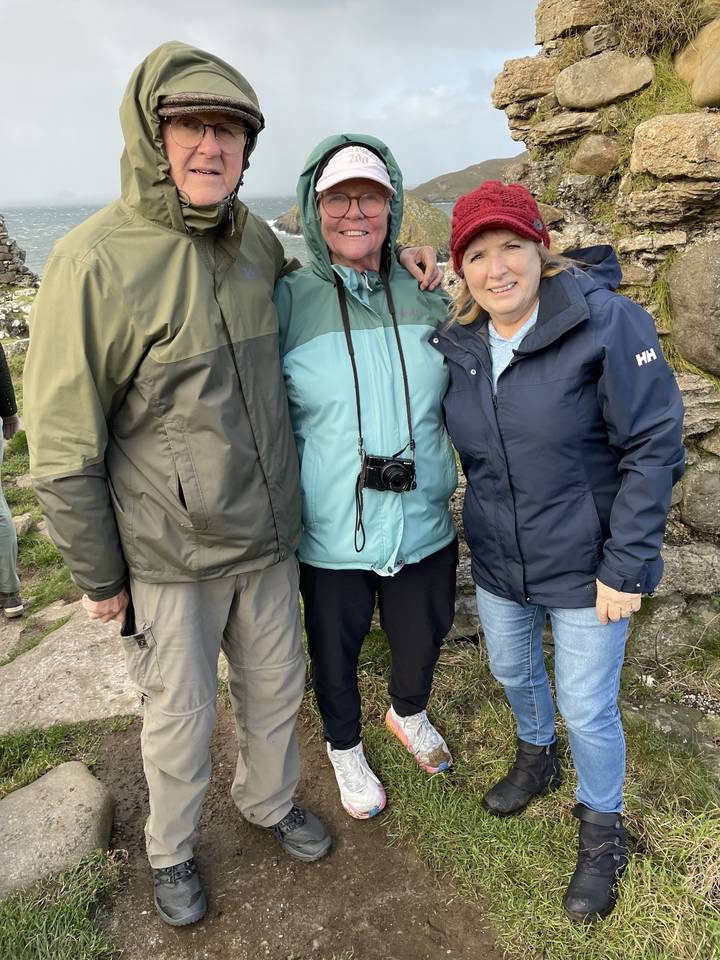Trois personnes posant sur une colline avec un paysage pittoresque en arrière-plan.