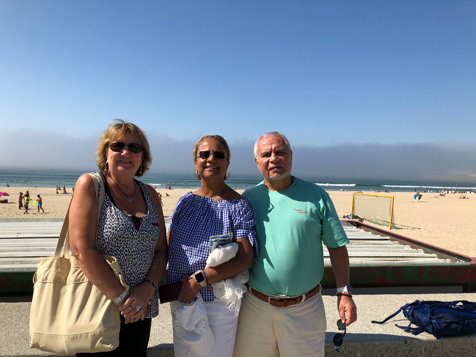 Trois personnes posant sur une plage avec vue sur l'océan.