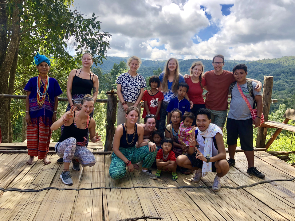 A group photo with locals in a scenic mountainous area.