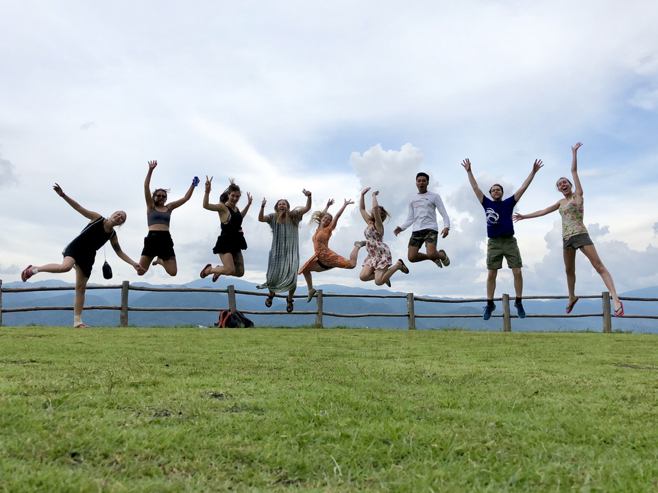 People joyfully jumping in the air with hills in the background.