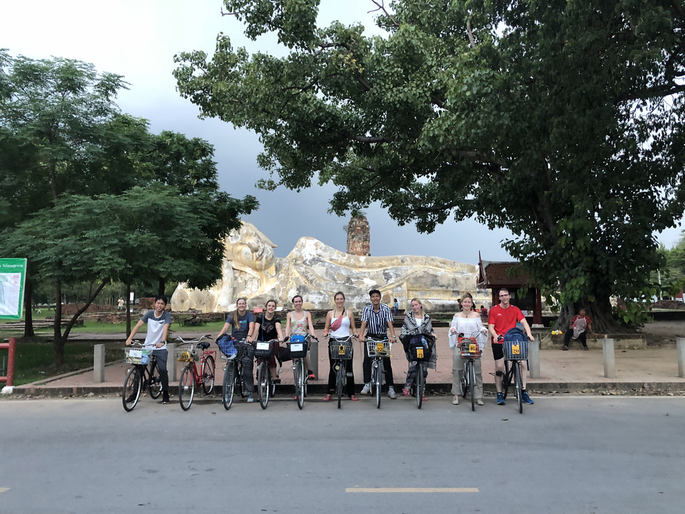 A group of people with bicycles posing in front of a large statue.
