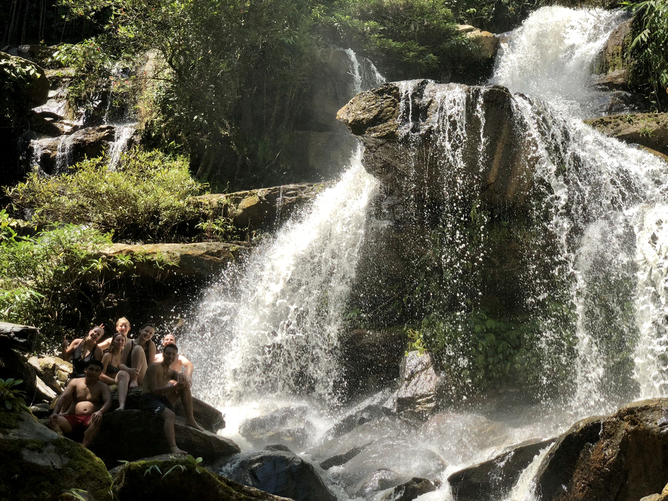 People sitting by a waterfall enjoying the spray of water.