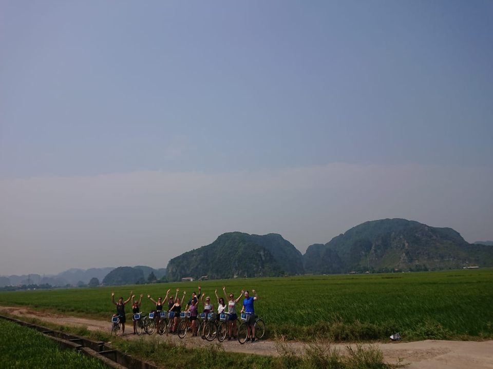 Group of people cheering in a field with mountains in the background.