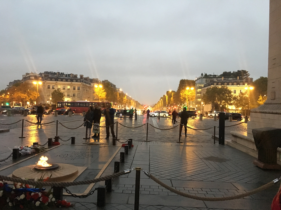 Place de ville animée avec éclairages du soir et gens qui se promènent.