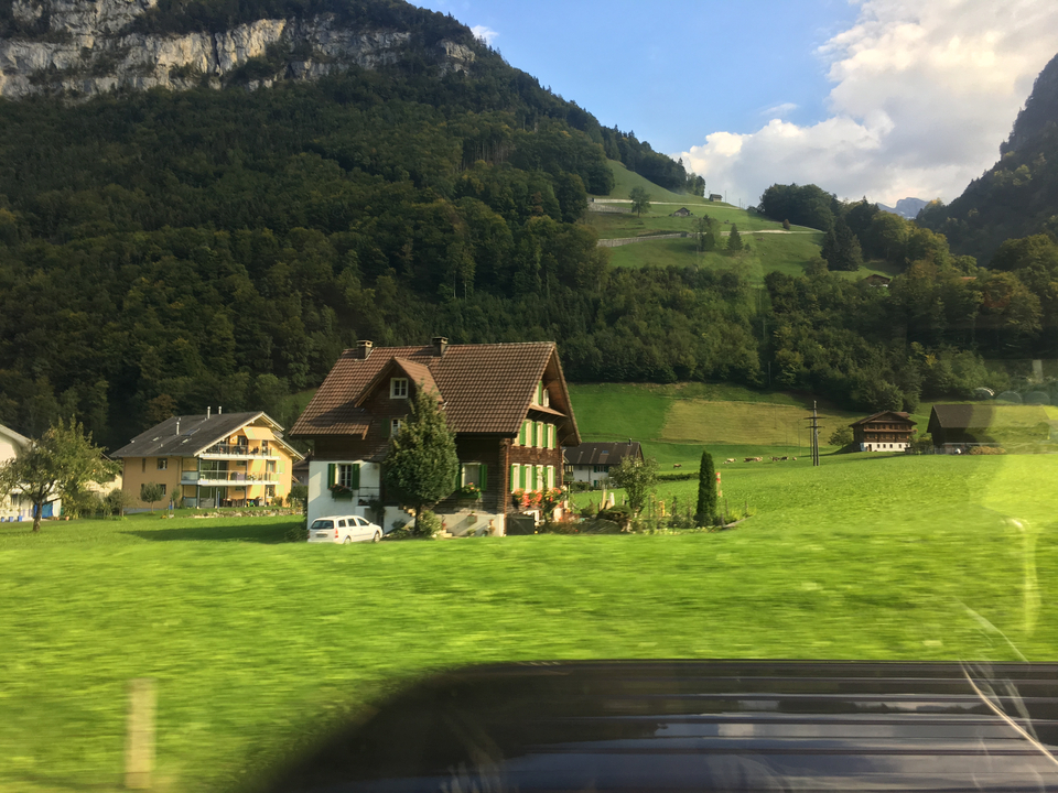 Maisons de village dans un paysage montagneux verdoyant.