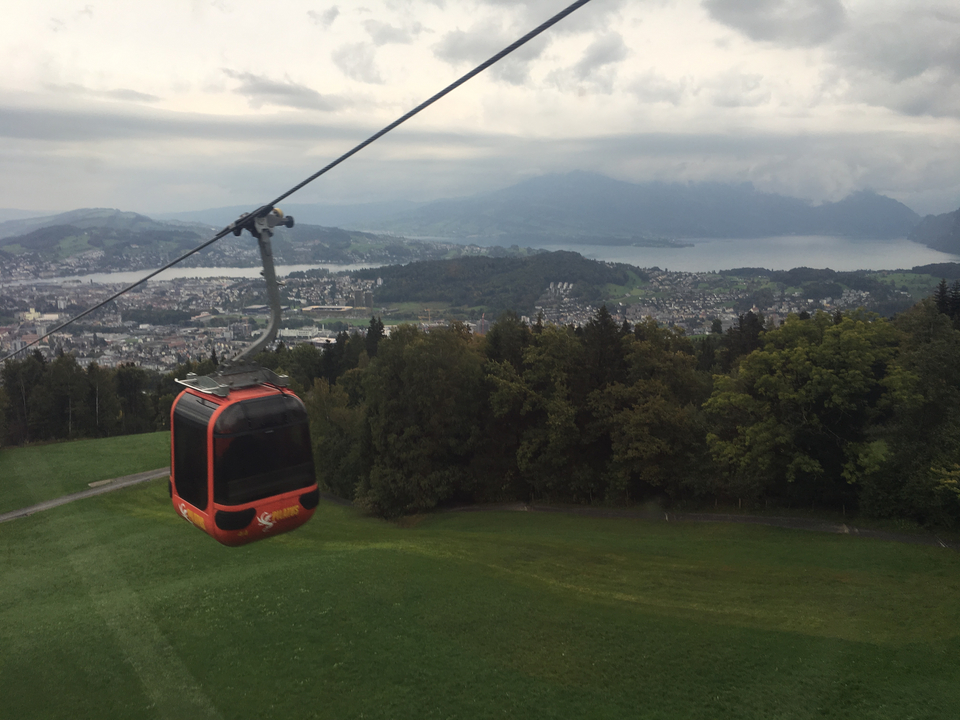 Téléphérique rouge dans un paysage montagneux surplombant un lac.