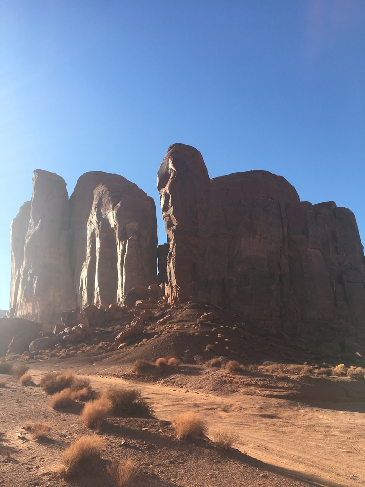 Monument Valley avec ses imposantes formations rocheuses sous un ciel bleu dégagé.