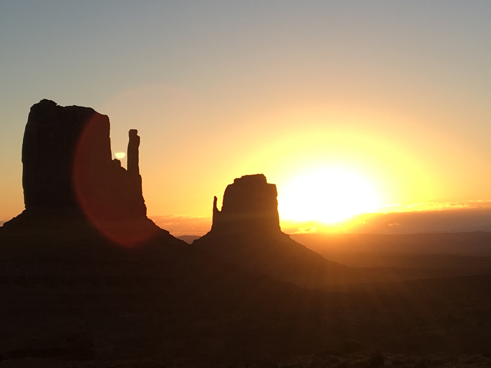 Coucher de soleil à Monument Valley avec des formations rocheuses en silhouette.