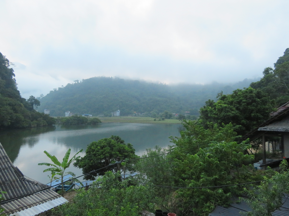 Lac calme avec montagnes et maisons dans la brume.
