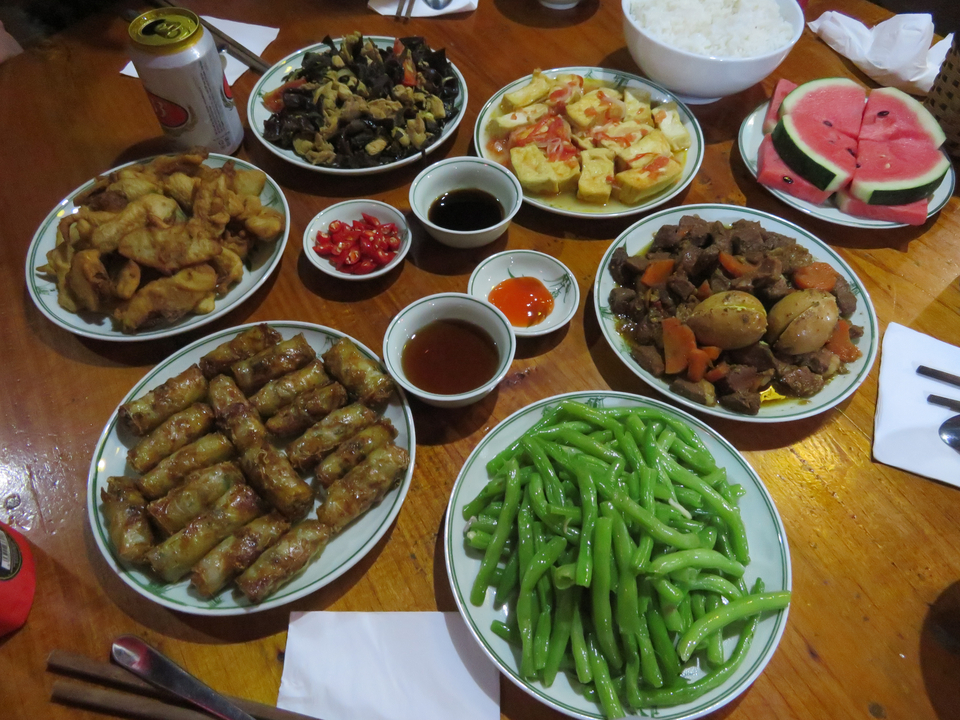 Plats variés incluant des rouleaux de printemps et des haricots sur une table en bois.