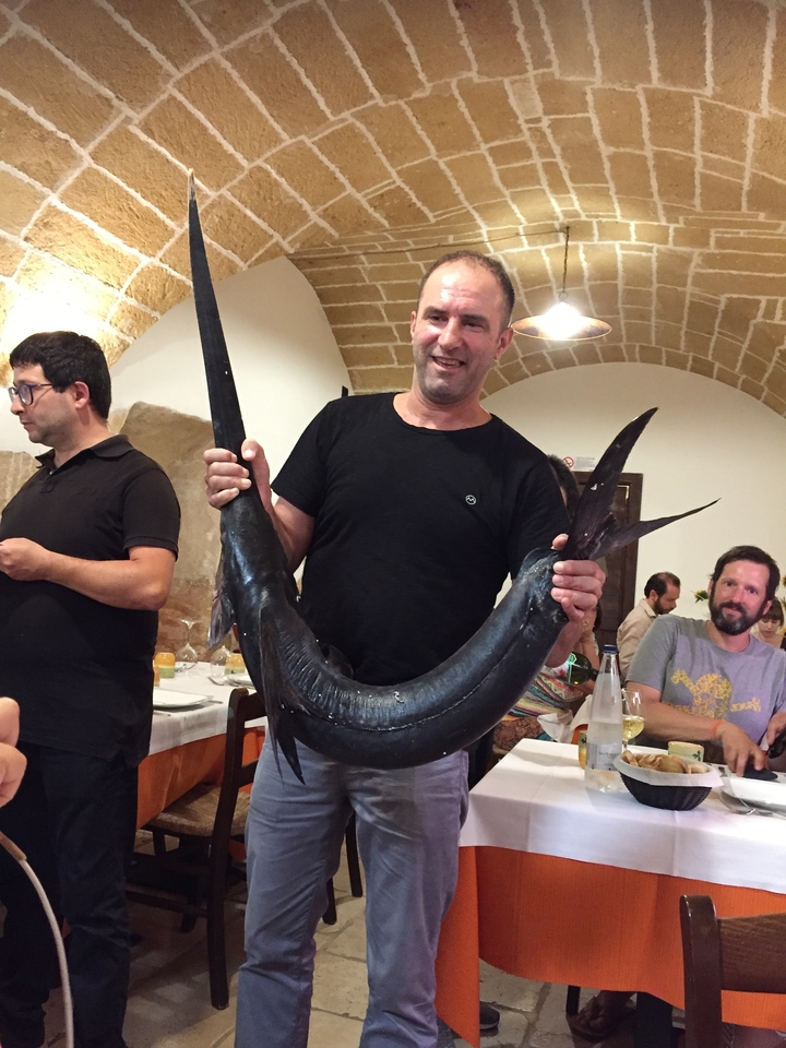 Personne tenant un gros poisson dans un cadre de restaurant.