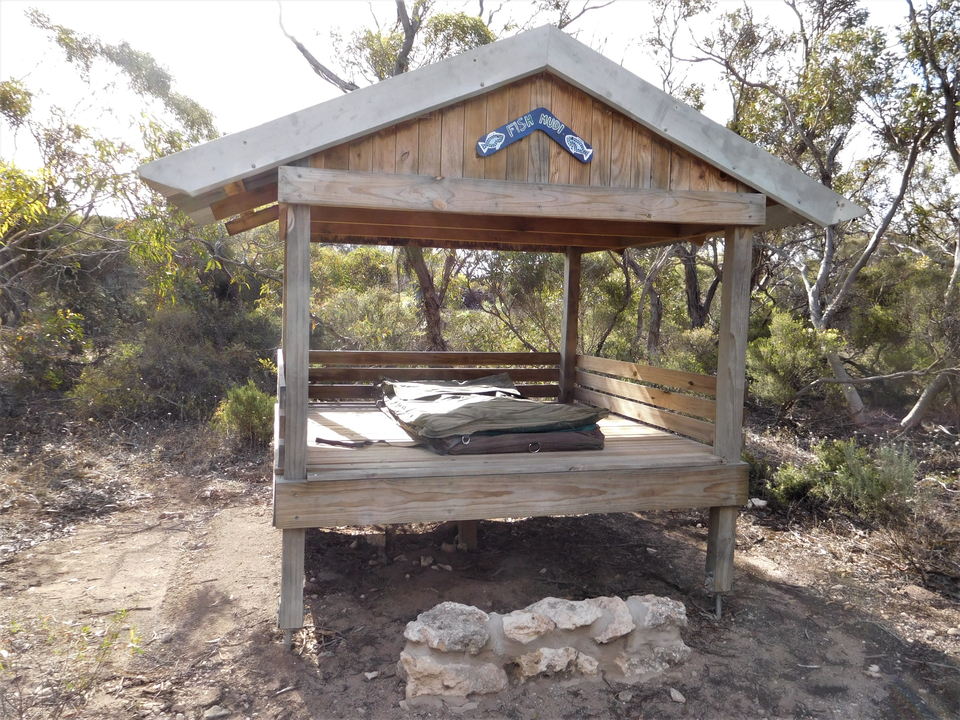Structure en bois ressemblant à une cabane avec un matelas à l'intérieur.