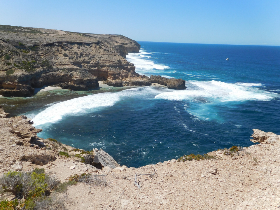 Côte rocheuse avec mer bleue et vagues déferlantes.