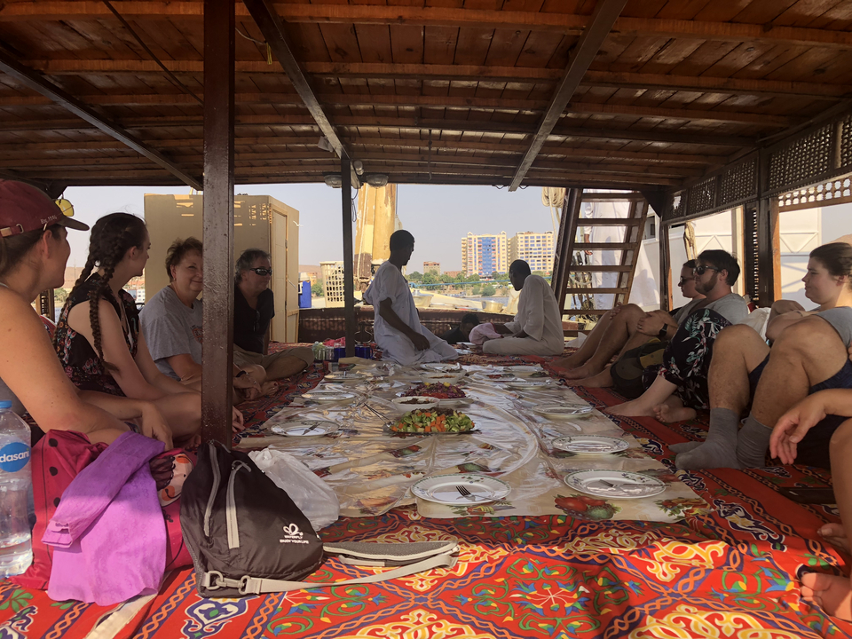 Groupe de personnes assises sur un bateau avec de la nourriture autour.