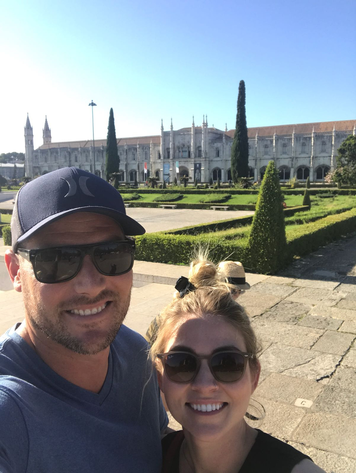 Selfie avec une personne devant un bâtiment orné et des jardins entretenus.