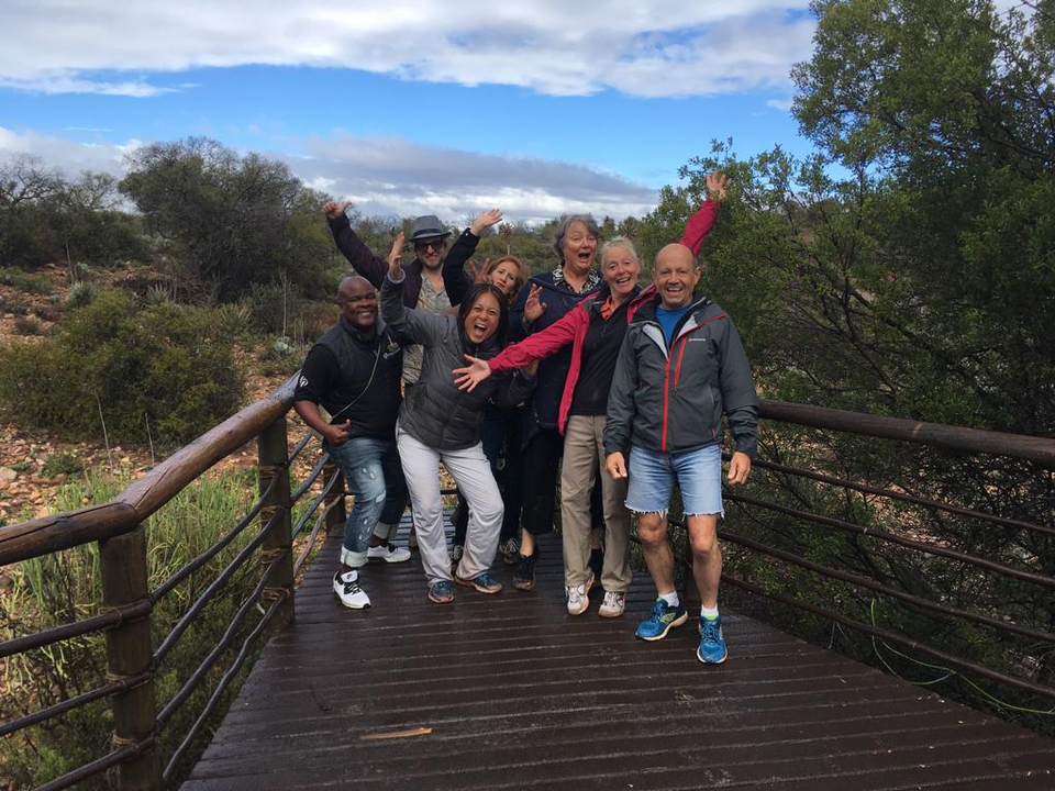 Excited group posing on a wooden bridge in a natural setting.