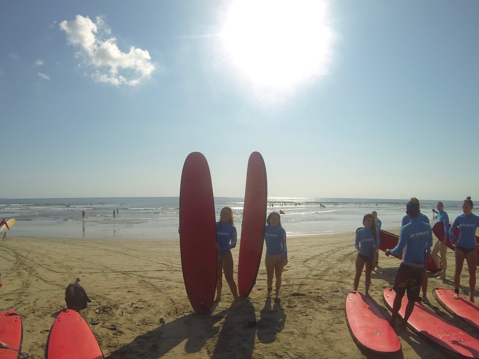Groupe de surfeurs sur une plage avec des planches contre le soleil.