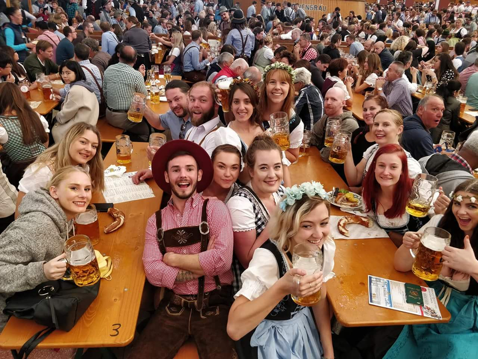 Groupe de personnes en tenues traditionnelles savourant de la bière lors d'un festival.