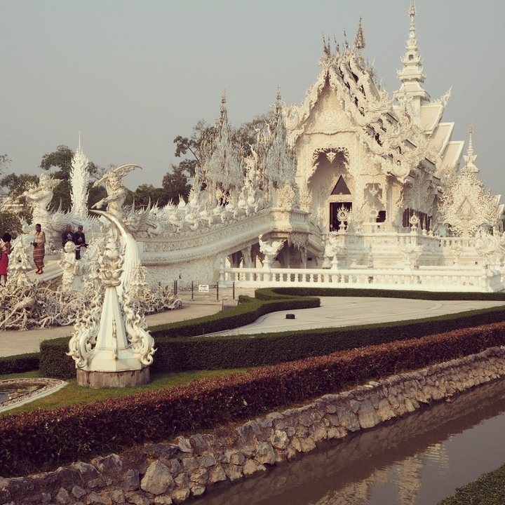 Temple blanc avec une architecture complexe et un paysage de jardin.