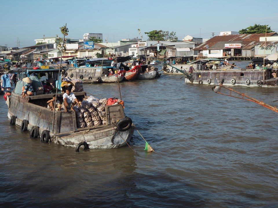 Marché animé au bord de la rivière avec des bateaux and des vendeurs sur une rivière.