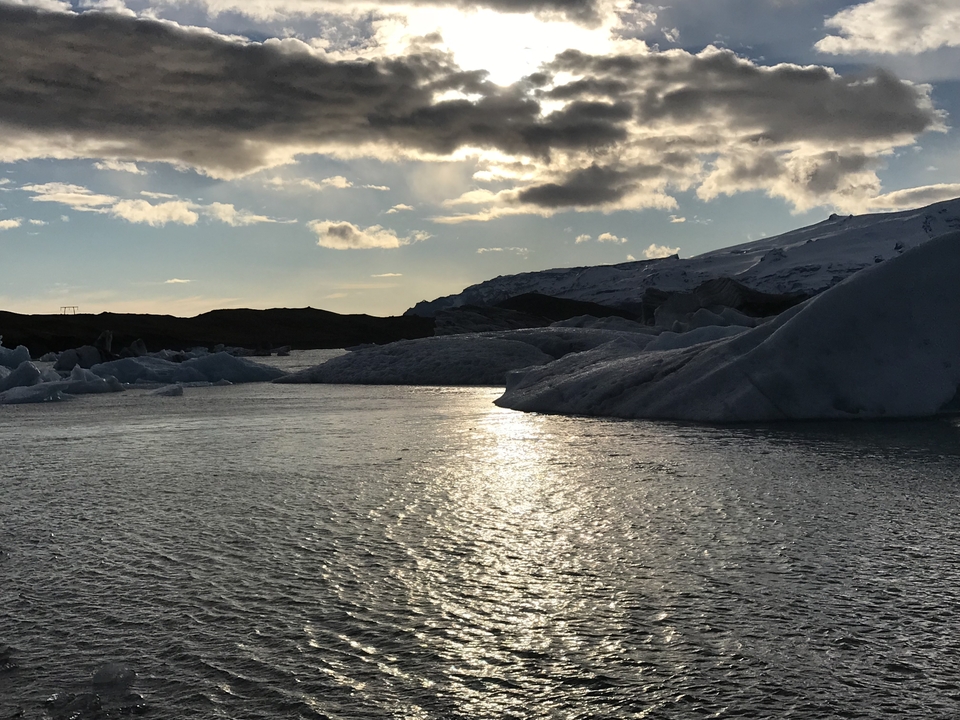 Vue panoramique d'un lagon glacé avec des icebergs et un ciel nuageux.