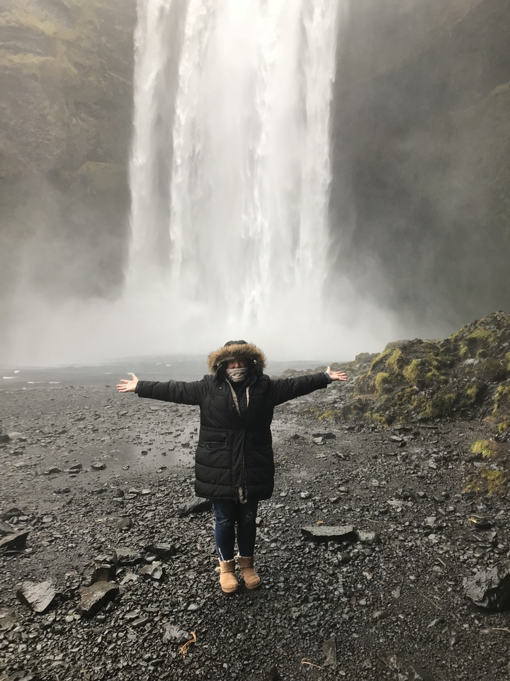 Personne posant devant une grande cascade.