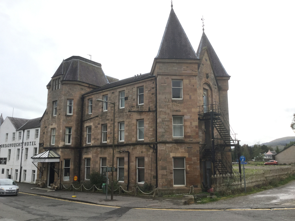 Un bâtiment historique en pierre avec des tourelles et un hôtel adjacent.