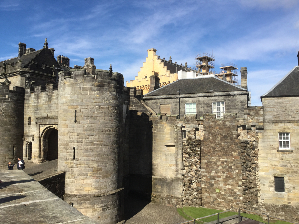 Un grand château de pierre avec des touristes qui se promènent à proximité.