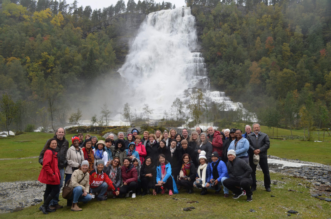 Un groupe de personnes posant devant une grande cascade.
