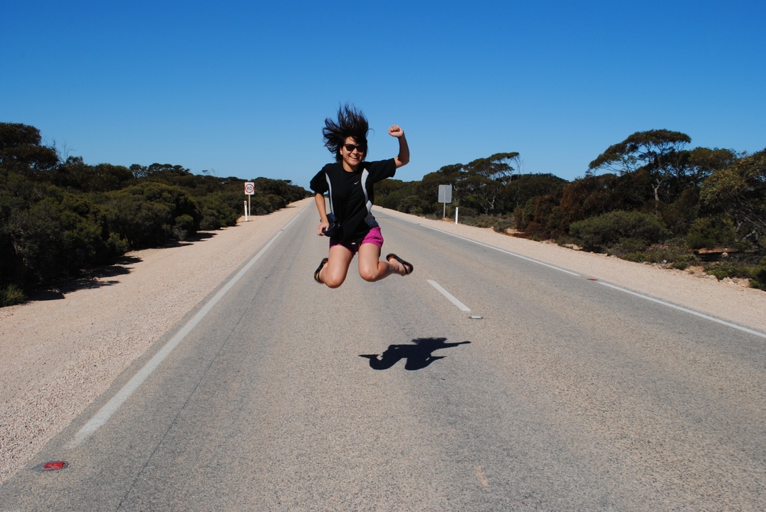 Personne sautant en l'air sur une route vide.