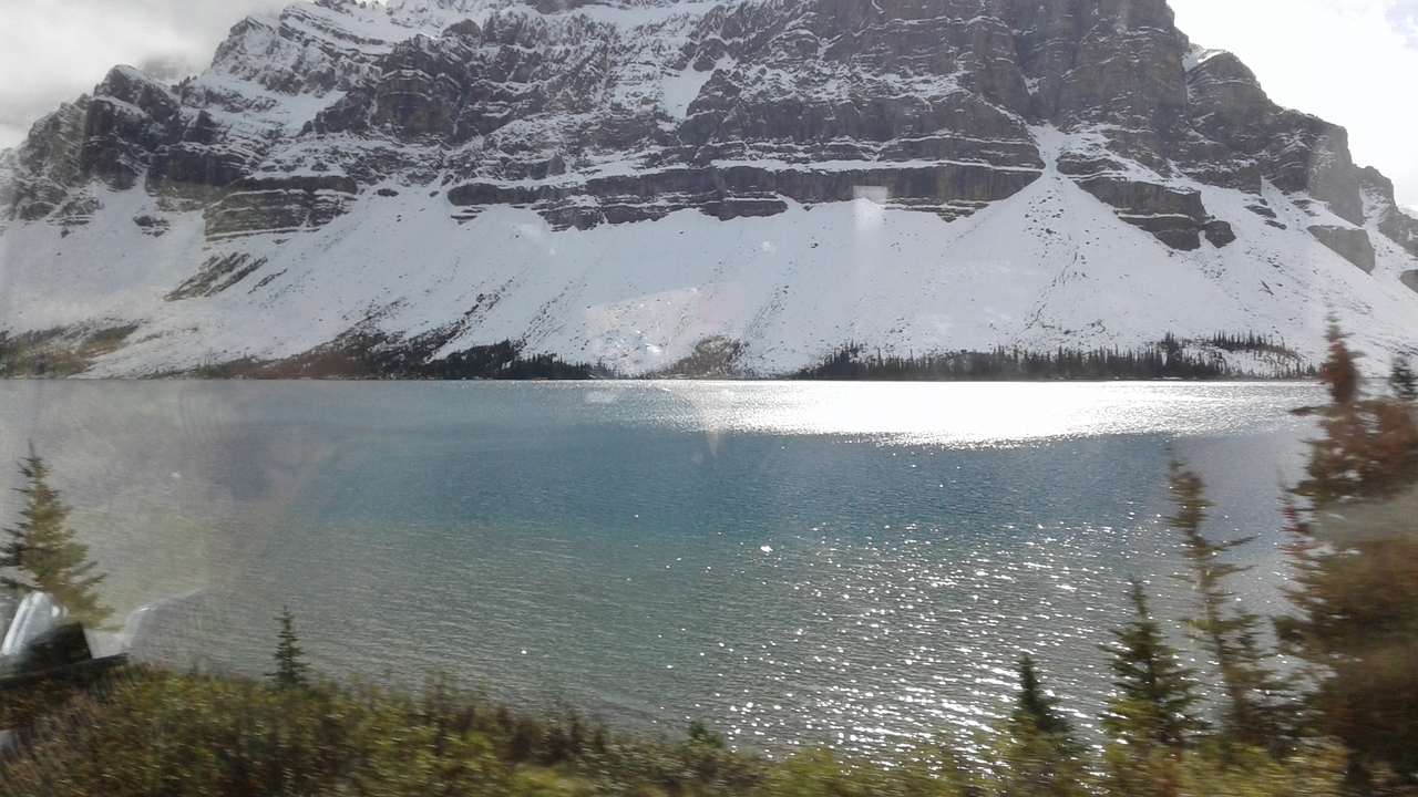 Montagnes enneigées avec un lac reflétant le ciel.