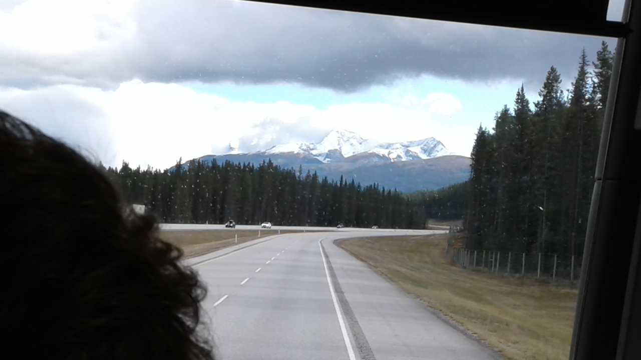 Vue d'autoroute avec des montagnes enneigées au loin.