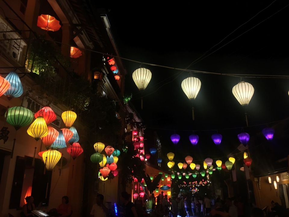 Des lanternes colorées suspendues dans une scène de rue nocturne.