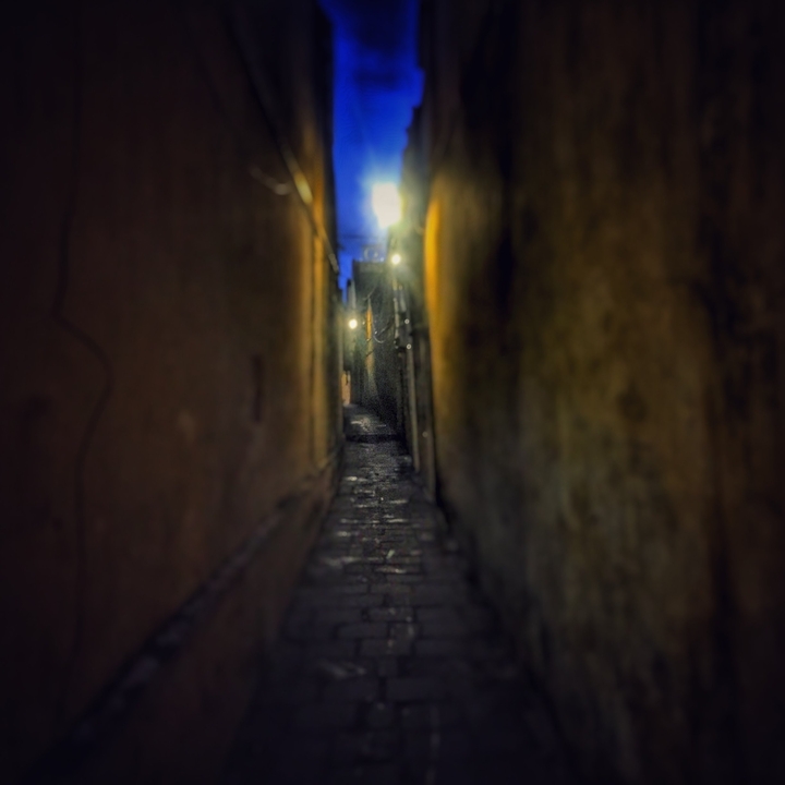 Ruelle étroite et faiblement éclairée avec un chemin de pierre.