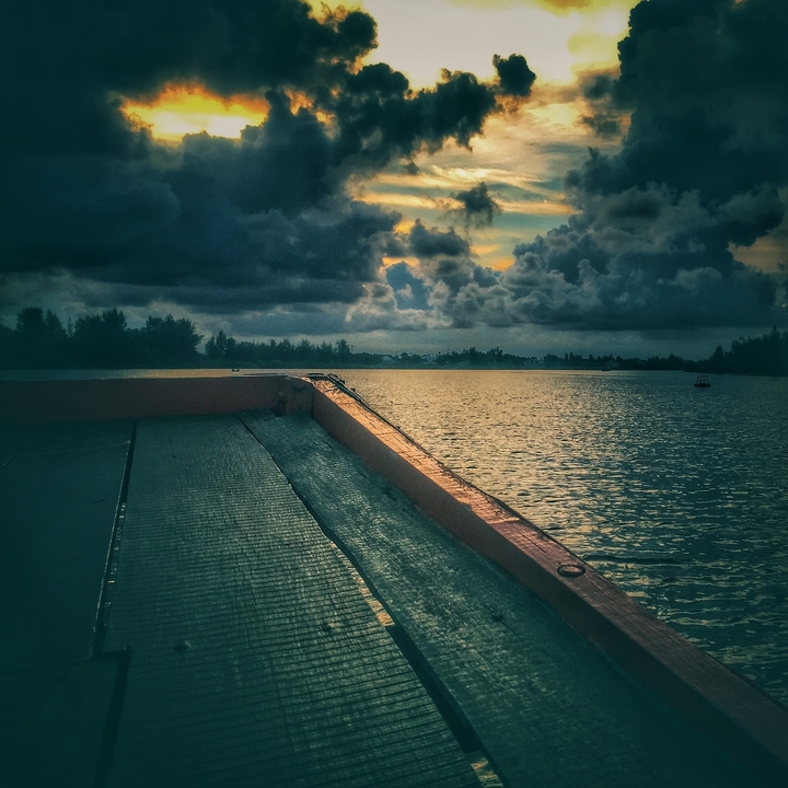 Bateau en bois sur une rivière sous un ciel nuageux dramatique.