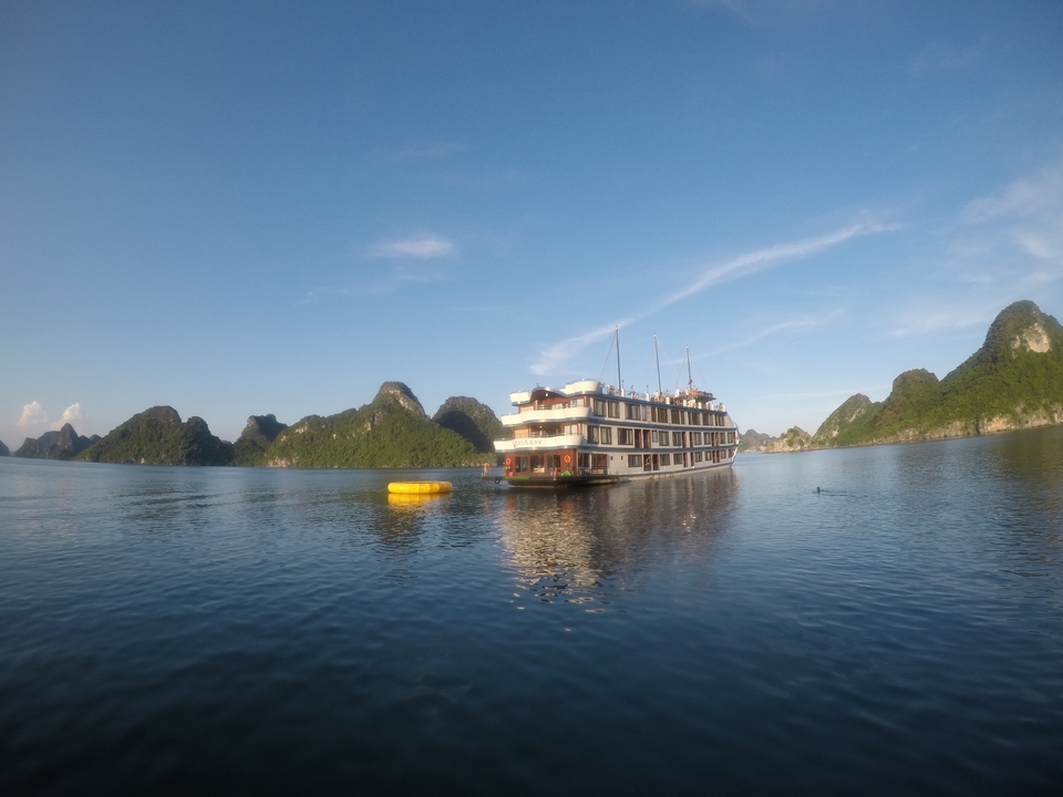 A large boat on calm ocean waters with island formations in the background.