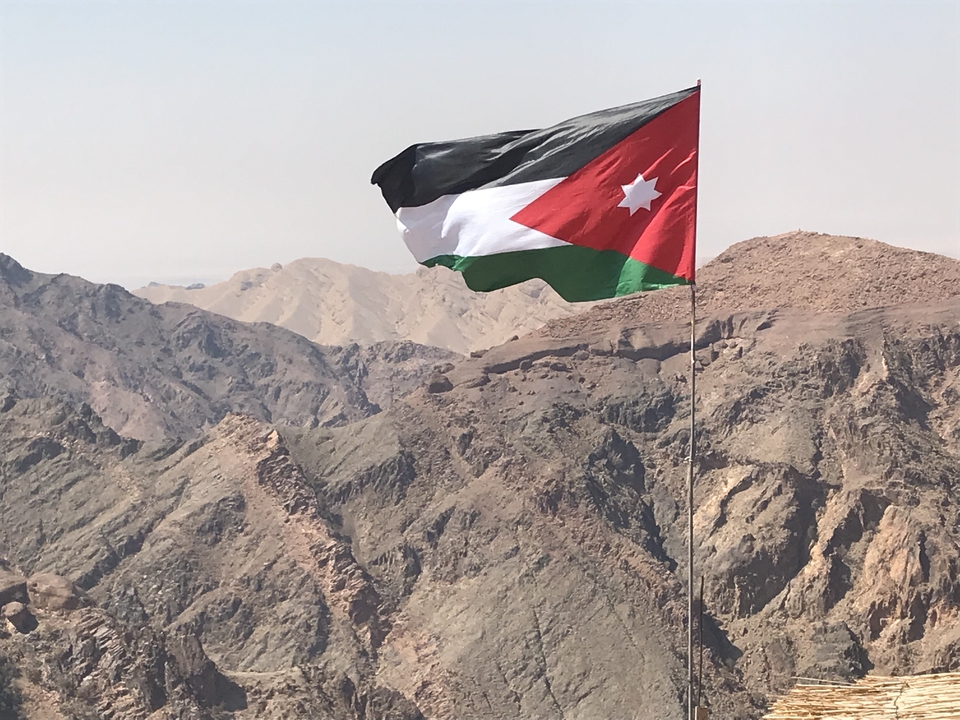 Drapeau jordanien flottant au-dessus d'un paysage montagneux.