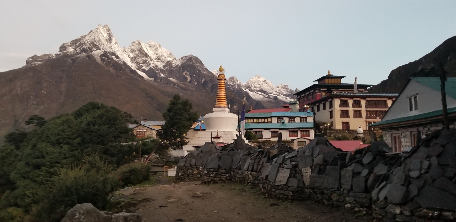 Village avec stupa et sommets montagneux enneigés sous un ciel clair.